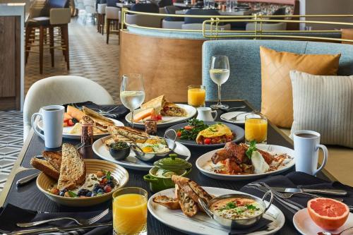 a table with plates of food and glasses of wine at Lively Hotel On Oak Oklahoma City, Tapestry By Hilton in Oklahoma City