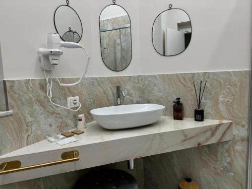 a bathroom with a white sink and two mirrors at InCentro Elegant Rooms in Messina