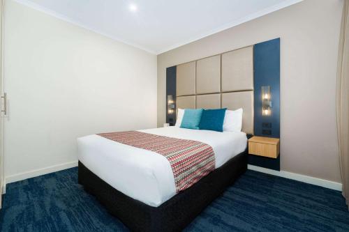 a bedroom with a large white bed with blue pillows at Quality Hotel Parklake Shepparton in Shepparton