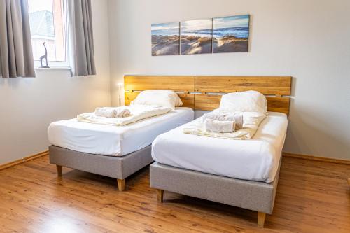 two twin beds in a room with wood floors at FineApartment Rendsburg in Rendsburg