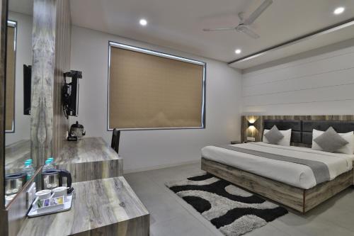 a bedroom with a bed and a large window at Hotel Limra Vadodara in Vadodara