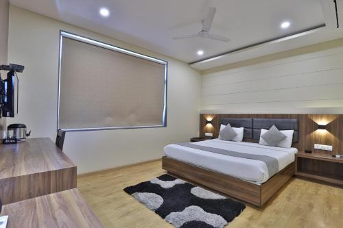 a bedroom with a bed and a large window at Hotel Limra Vadodara in Vadodara