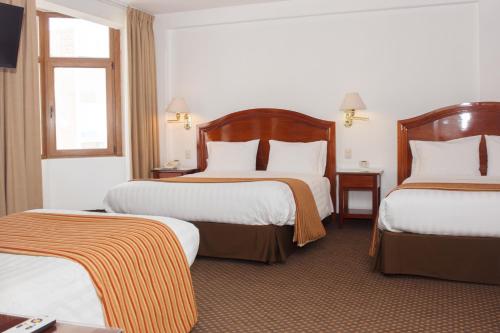 a hotel room with two beds and two windows at Hotel Hacienda Puno Centro Histórico in Puno
