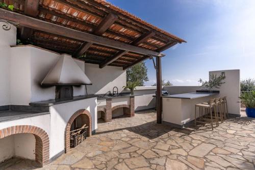 a patio with an outdoor kitchen with an outdoor grill at Villa Chez Piè Panoramic Views Pool and Guest Services in SantʼAgata sui Due Golfi