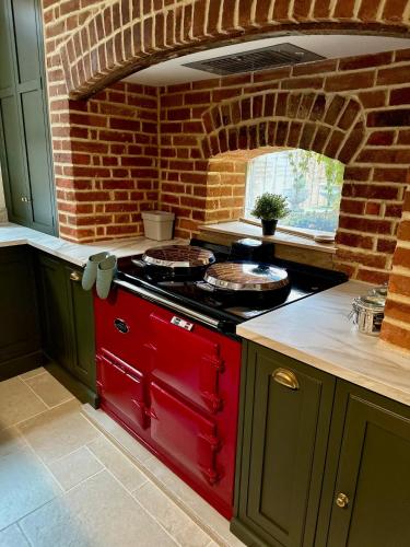 a kitchen with a red stove and a brick wall at Oxford Grade II listed house in Woodstock