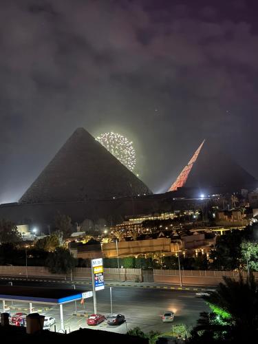 a pyramid with a firework display behind it at night at Unique Pyramids Boutique INN in Cairo