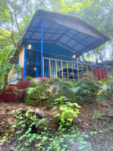 a house with a blue roof and some plants at Samyama Retreat in Cola