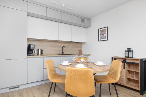 a kitchen with a table and chairs in a room at Szczeciński Apartament Kwiatkowskiego w Spokojnej Okolicy by Noclegi Renters in Szczecin