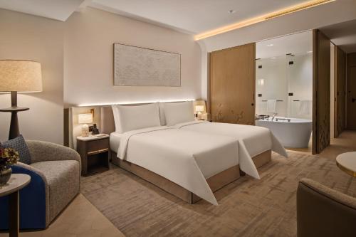 a bedroom with a large white bed and a bath tub at Palace Dubai Creek Harbour in Dubai