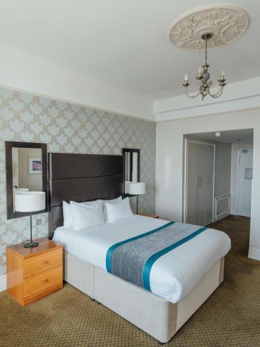 a bedroom with a large bed and a chandelier at Queens Hotel & Spa in Brighton & Hove