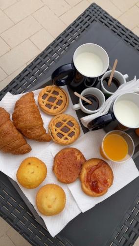 Una mesa con una bandeja de pasteles, pan y leche. en MARVIT CENTRAL LUXURY, en Nápoles