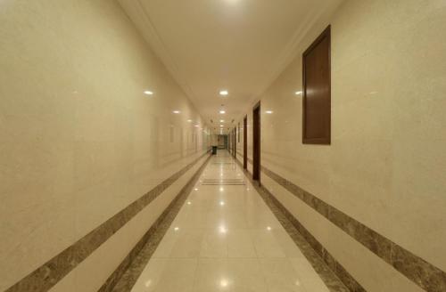 a long hallway with white floors and a person walking down it at فندق سيف بلص 2 من اورفانا in Makkah