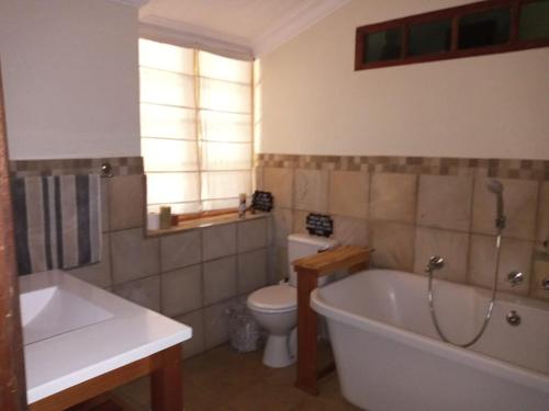 Un baño con bañera, inodoro y lavabo. en A2B Eco Farm, Byrne Valley, KZN, en Byrne