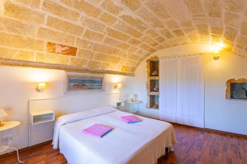 a bedroom with a white bed with a stone ceiling at Villa Tenuta Ai Fichi con piscina esclusiva in Leuca