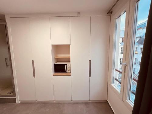 une armoire blanche dans une chambre avec un four micro-ondes dans l'établissement Charming Studio near Châtelet Saint Sauveur, à Paris