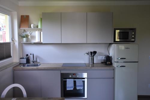 a kitchen with white cabinets and a sink and a refrigerator at HOMEBOUND APARTMENTS Salzburg City II - contactless check-in in Salzburg