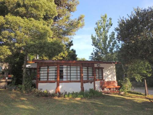 a small cabin with a bench in the grass at Cabañas Gesell in Villa Gesell