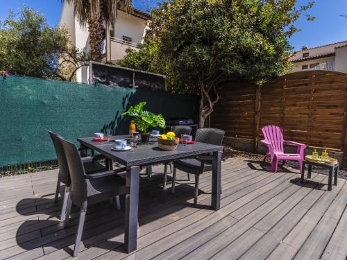 une terrasse en bois avec une table et des chaises. dans l'établissement Apartment Les Grenadines-2 by Interhome, au Cap d'Agde