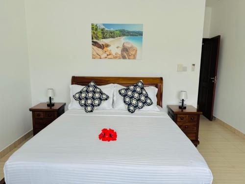 a bedroom with a bed with a red flower on it at Bijoutier Apartments in Grand'Anse Praslin