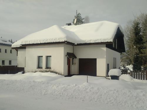 a white house with snow on top of it at Cottage House in Stožec