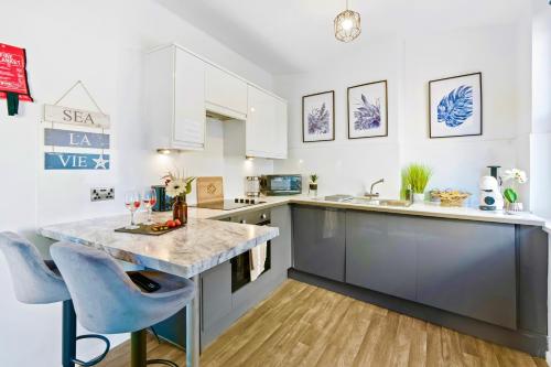a kitchen with a large counter and blue chairs at Modern 1-Bed Serviced Apartment - Central Brighton in Brighton & Hove