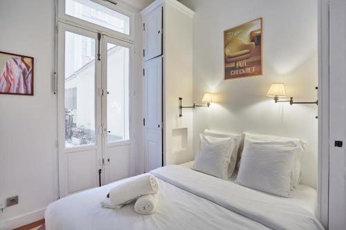 une chambre avec un lit avec des draps blancs et une fenêtre dans l'établissement Appartment St Germain des pres by Studio Prestige, à Paris