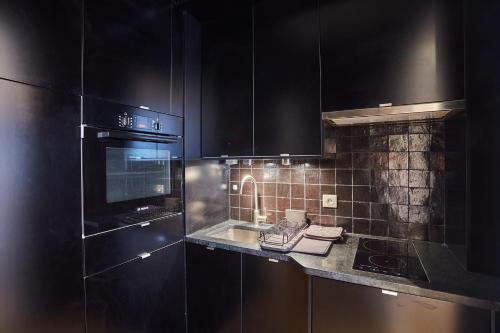 une cuisine avec des armoires noires et un four à plaques de cuisson dans l'établissement Appartment St Germain des pres by Studio Prestige, à Paris