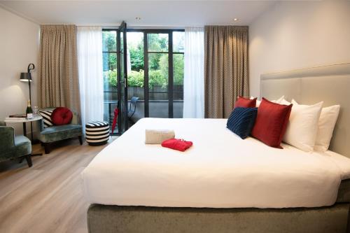 a bedroom with a large white bed with red pillows at Maison ELLE Amsterdam in Amsterdam