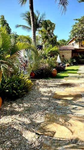 a garden with palm trees and plants and a house at Villa Biju in Jericoacoara