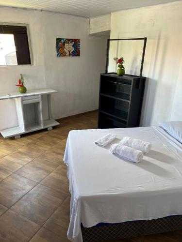 a bedroom with a white bed with towels on it at Destino Hospeda in Pipa