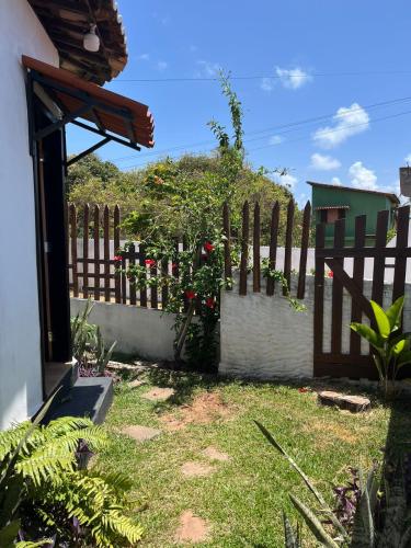 a fence with red roses on it next to a yard at Destino Hospeda in Pipa