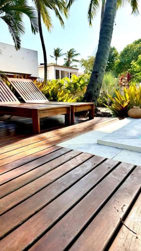 two wooden benches sitting on a deck with palm trees at Villa Biju in Jericoacoara