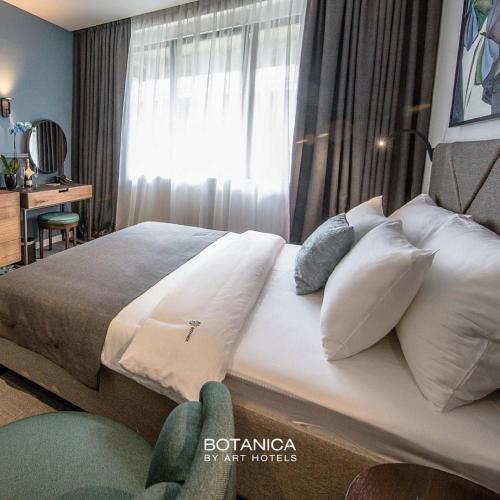 a bedroom with a bed with white pillows and a window at Hotel Botanica in Belgrade