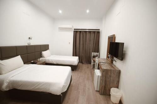 a hotel room with two beds and a television at Red Sea Hotel in Būr Tawfīq