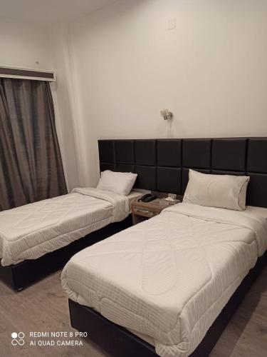 two beds in a hotel room with white sheets at Red Sea Hotel in Būr Tawfīq