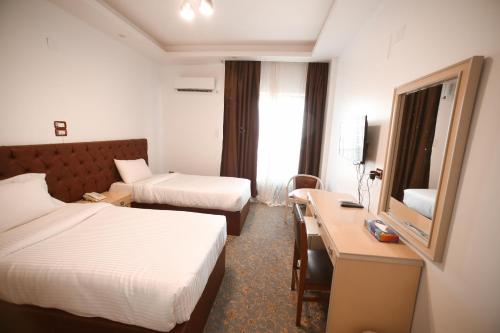 a hotel room with two beds and a desk at Red Sea Hotel in Būr Tawfīq
