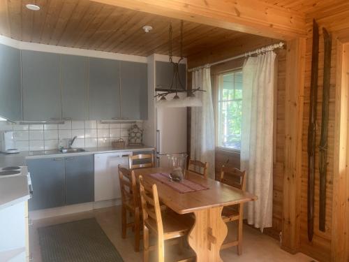 a kitchen with a wooden table and a dining room at Tahkon Riihiranta - 4 bedroom villa with lake view - Tilava mökki rantanäkymin in Tahkovuori