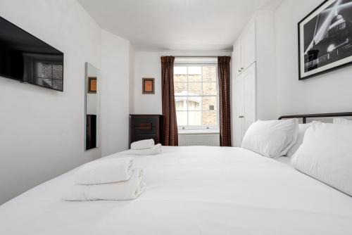 a white bedroom with a large bed and a window at GuestReady - Lovely stay in the heart of London in London