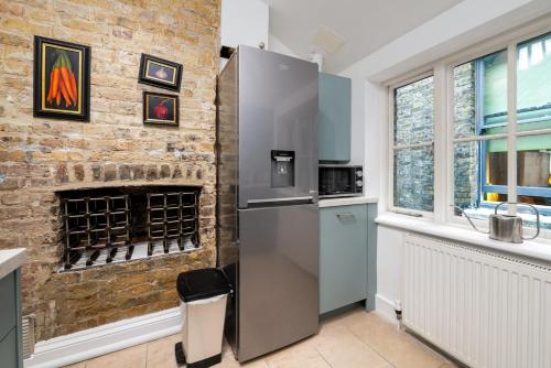 a stainless steel refrigerator in a kitchen with a brick wall at GuestReady - Lovely stay in the heart of London in London