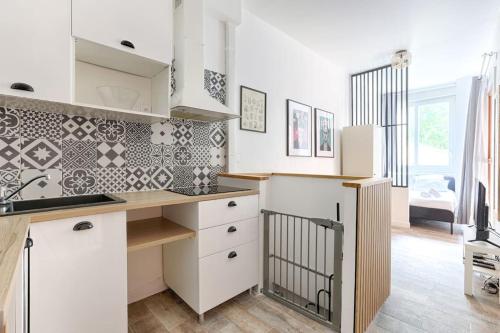 une cuisine avec des armoires blanches et un comptoir dans l'établissement République Canal St Martin Charming Apartment, à Paris