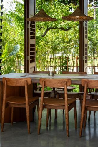 a wooden table and chairs with a large window at Nongnia Beach Villa in Tân Thành (1)