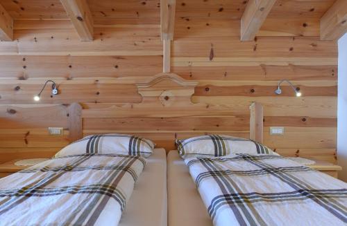 two beds in a room with wooden walls at Agriturismo Soleseid in San Vigilio Di Marebbe