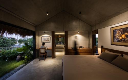 un dormitorio con una cama y una persona sentada en una silla en Nongnia Beach Villa, en Tân Thành (1)