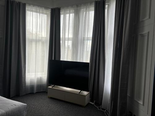 a tv sitting in a room with windows at Hotel Baba in Uddingston