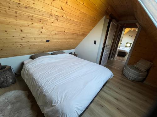 a white bed in a room with a wooden ceiling at Wildenburgs klaverhuisje in Wingene