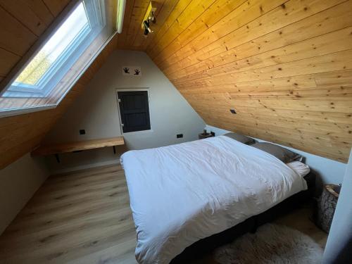 an attic bedroom with a bed and a wooden ceiling at Wildenburgs klaverhuisje in Wingene