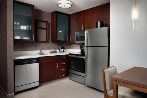 a kitchen with a stainless steel refrigerator and wooden cabinets at Residence Inn by Marriott Austin Lake Austin/River Place in Four Points