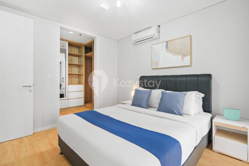 a white bedroom with a blue and white bed at Bialy by Kozystay - Alam Sutera in Tangerang