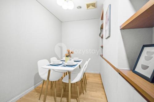 a dining room with a white table and white chairs at Bialy by Kozystay - Alam Sutera in Tangerang