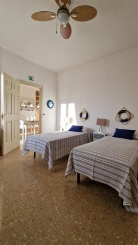 een slaapkamer met twee bedden en een plafondventilator bij Portuense1499 in Ponte Galeria